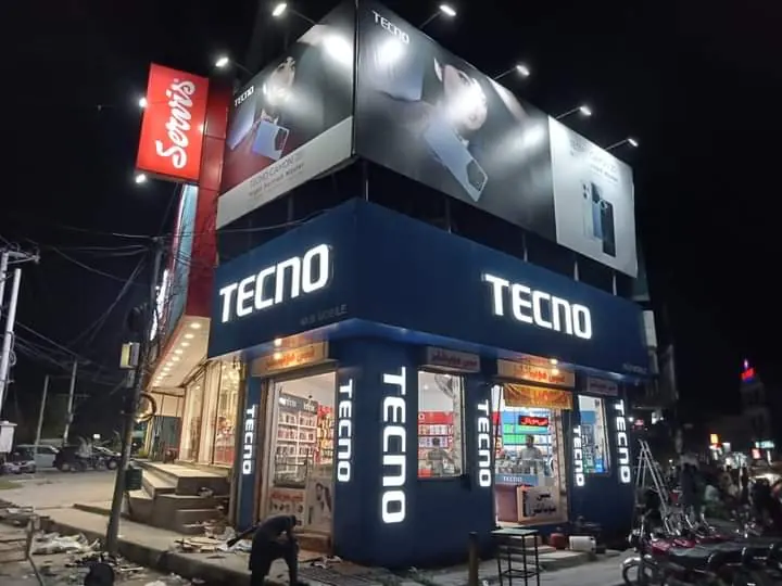 A corner phone shop at night with a lit fascia board
